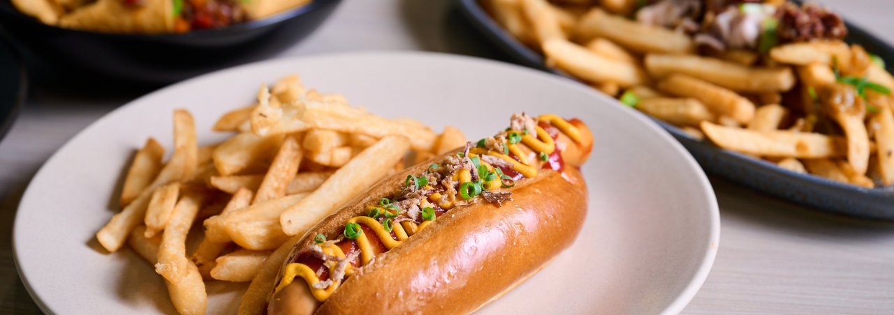 Hot dog and chips in the foreground with loaded fries and nachos in the background